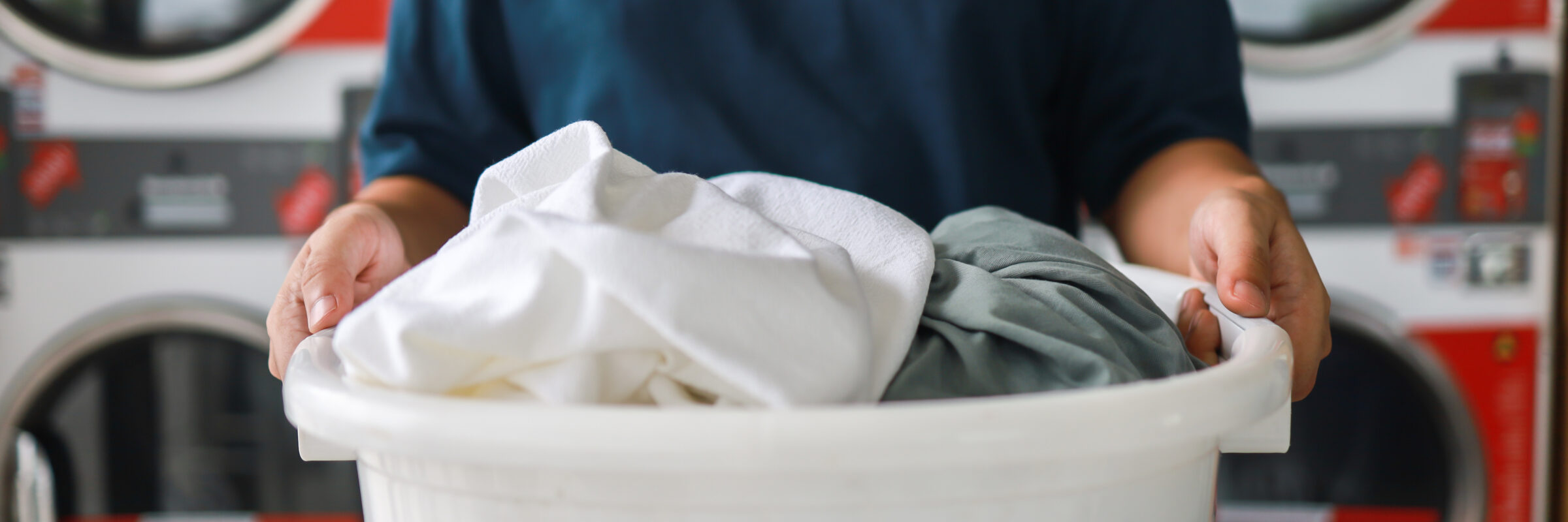Man doing launder holding basket with dirty laundry of the washing machine in the public store. laundry clothes concept